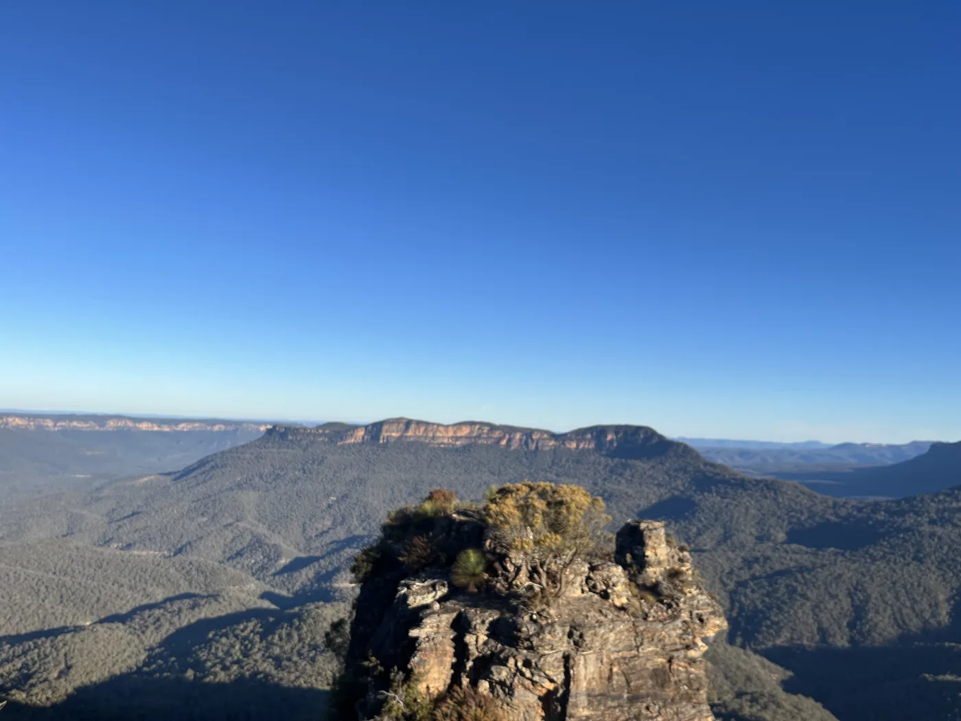 Rocky outcrop in the foreground with the vast forested Blue Mountains valley stretching to the horizon