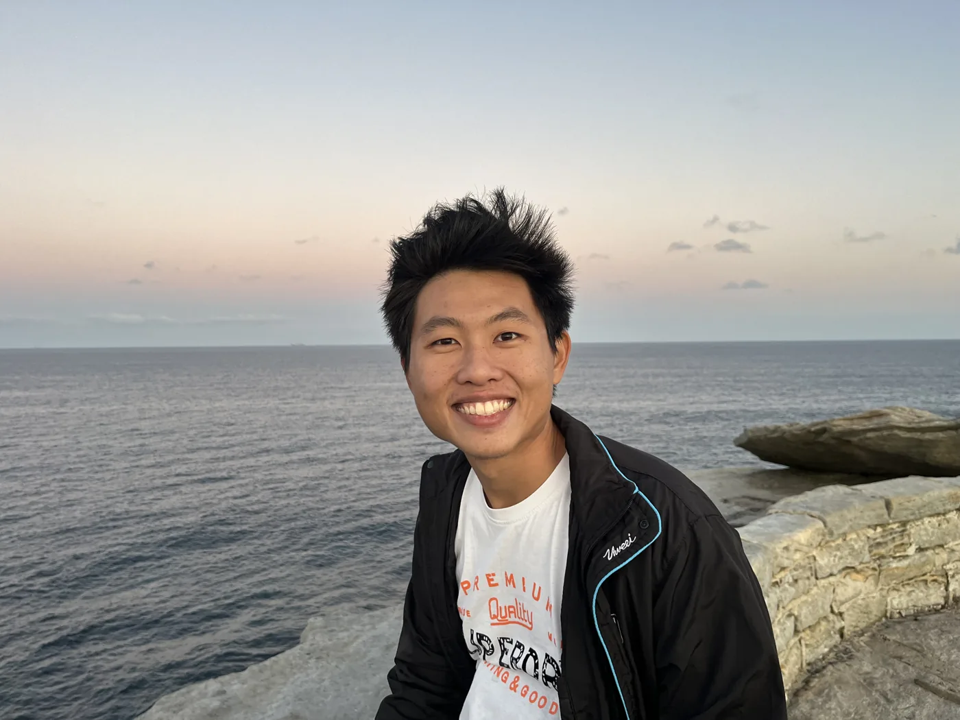 Smiling on coastal sandstone rocks at dusk with the Pacific Ocean behind