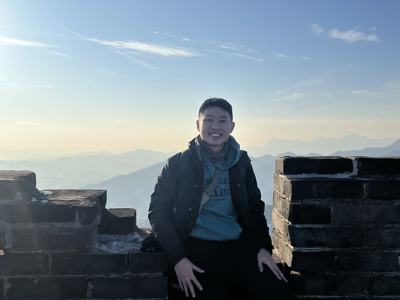 Sitting on a Great Wall watchtower in winter with mountain ranges behind