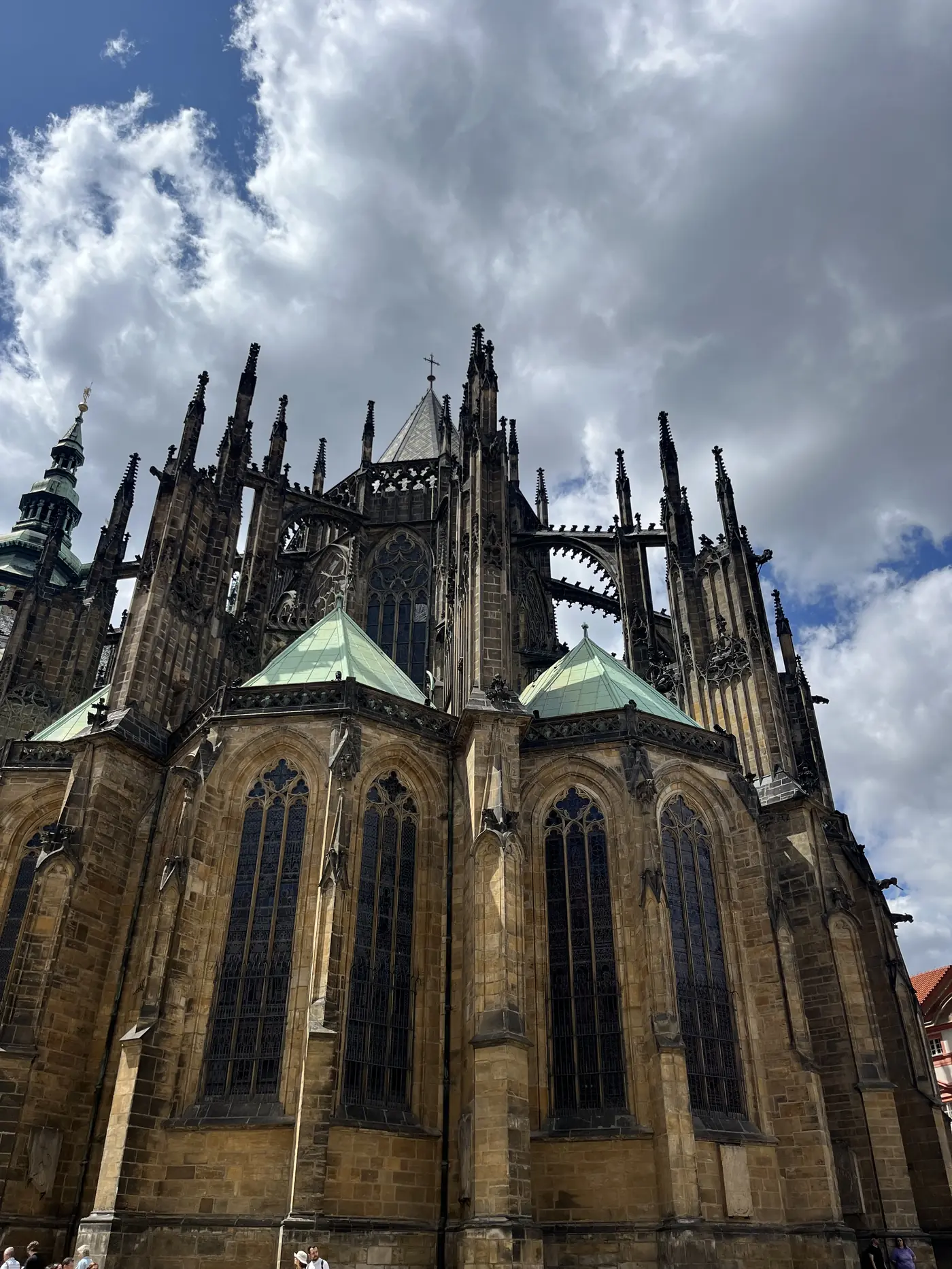 Close-up view of St. Vitus Cathedral's Gothic flying buttresses and stone spires against a dramatic cloudy sky
