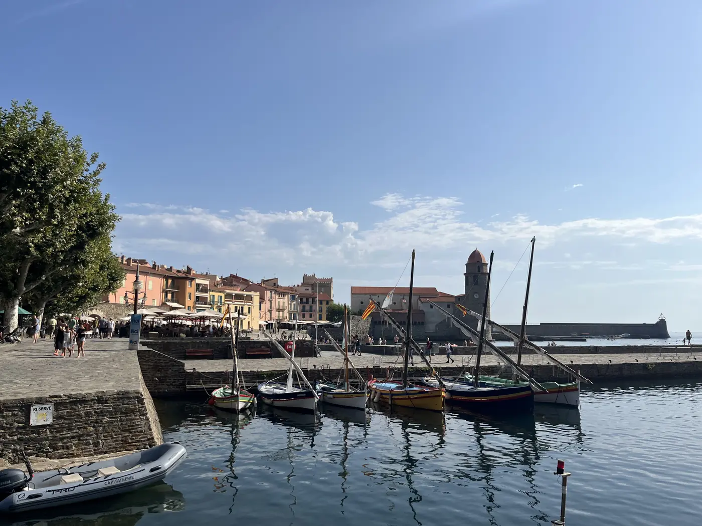 Collioure harbour with traditional wooden fishing boats moored in front of the bell tower of Notre-Dame-des-Anges church