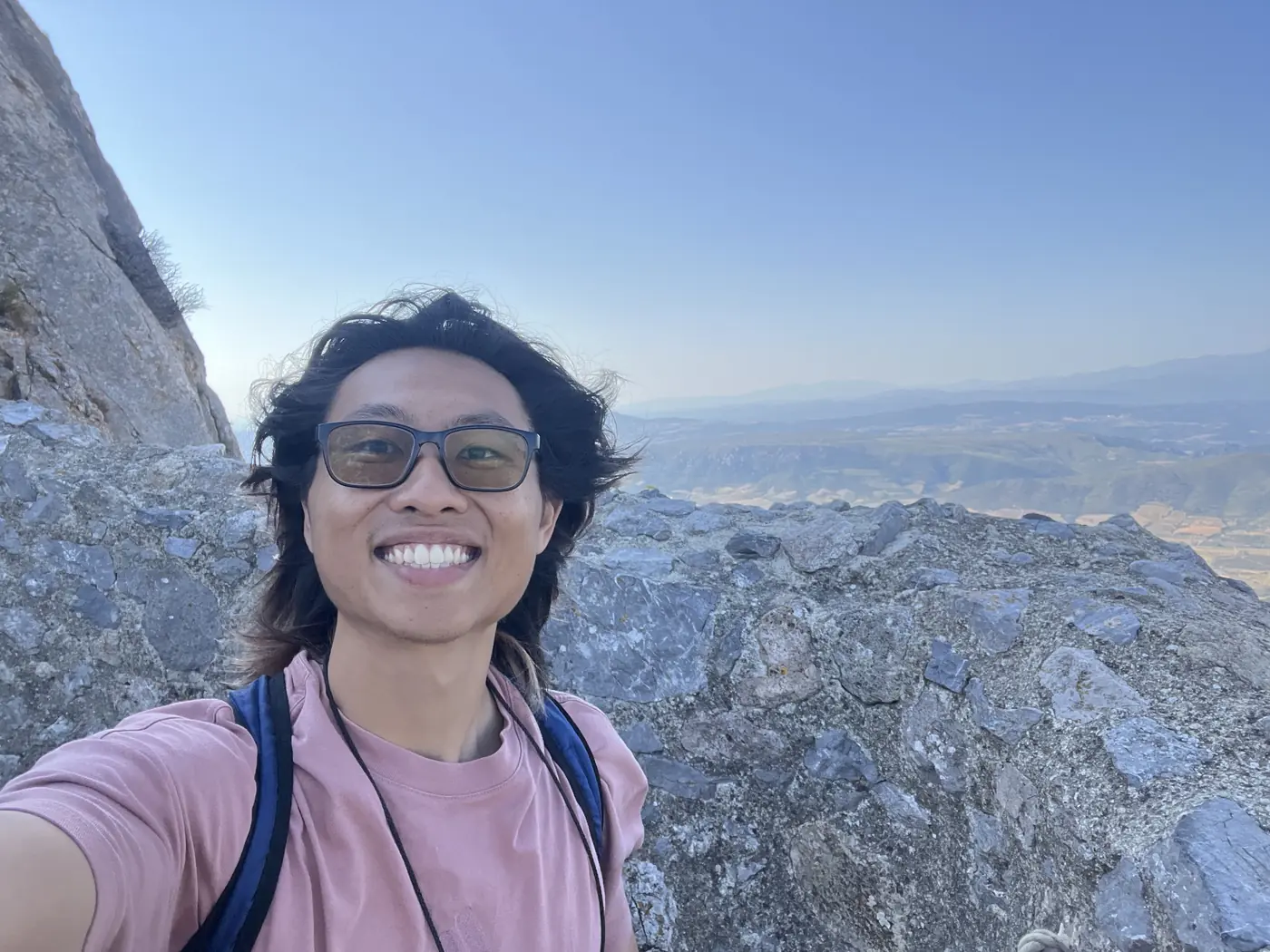 Shin selfie atop a rocky Cathar castle ruin in the Corbières, mountains and valley stretching into the haze behind him