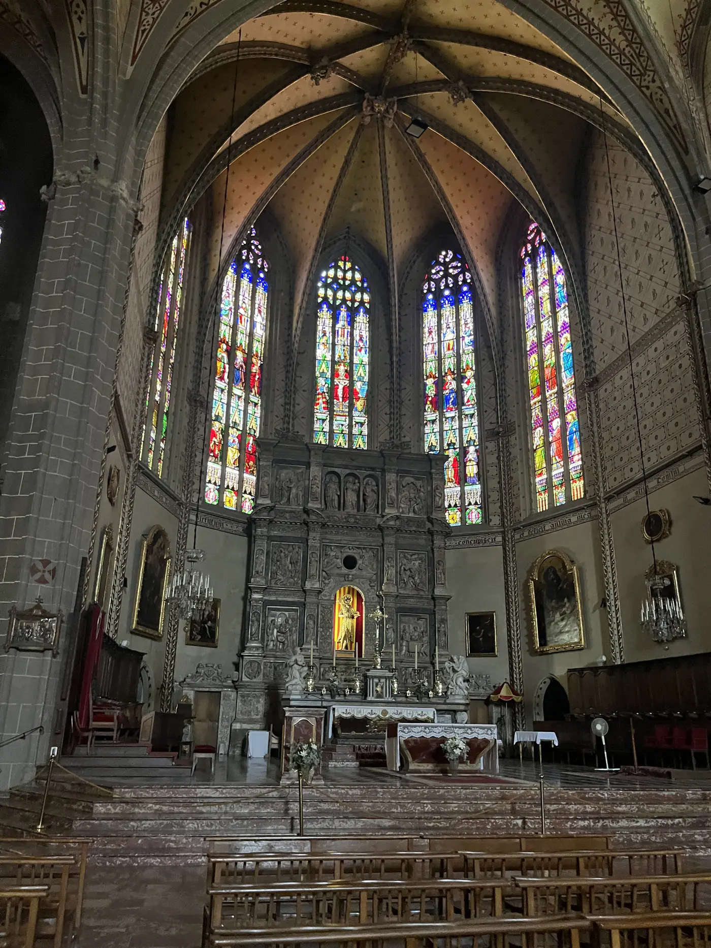 Interior of Perpignan Cathedral (Saint-Jean-Baptiste), gothic vaulted ceiling and tall stained-glass windows above the altar