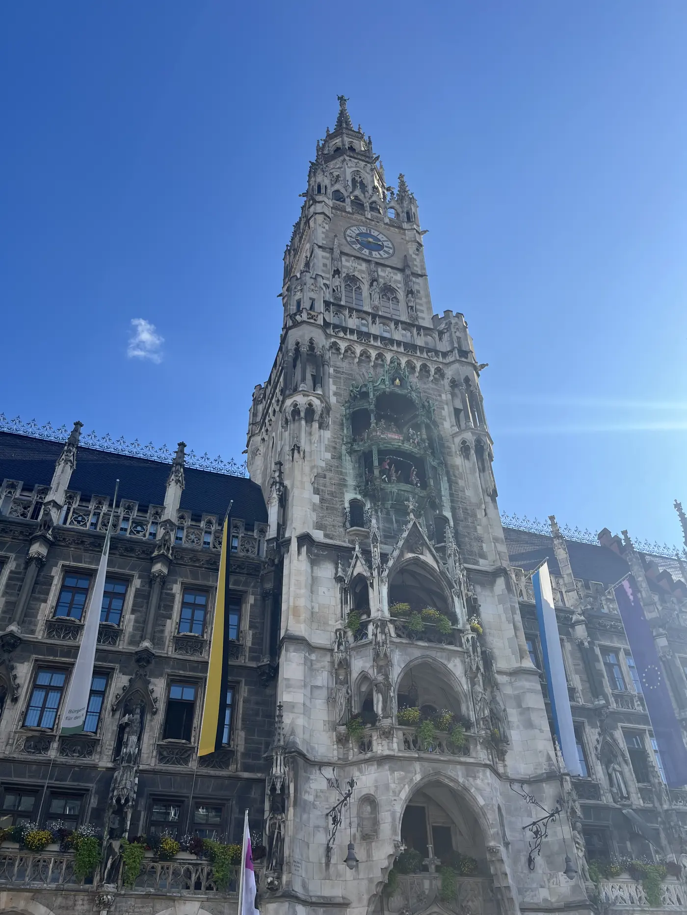 The Gothic Glockenspiel tower of Munich's New Town Hall on Marienplatz, rising against a clear blue sky