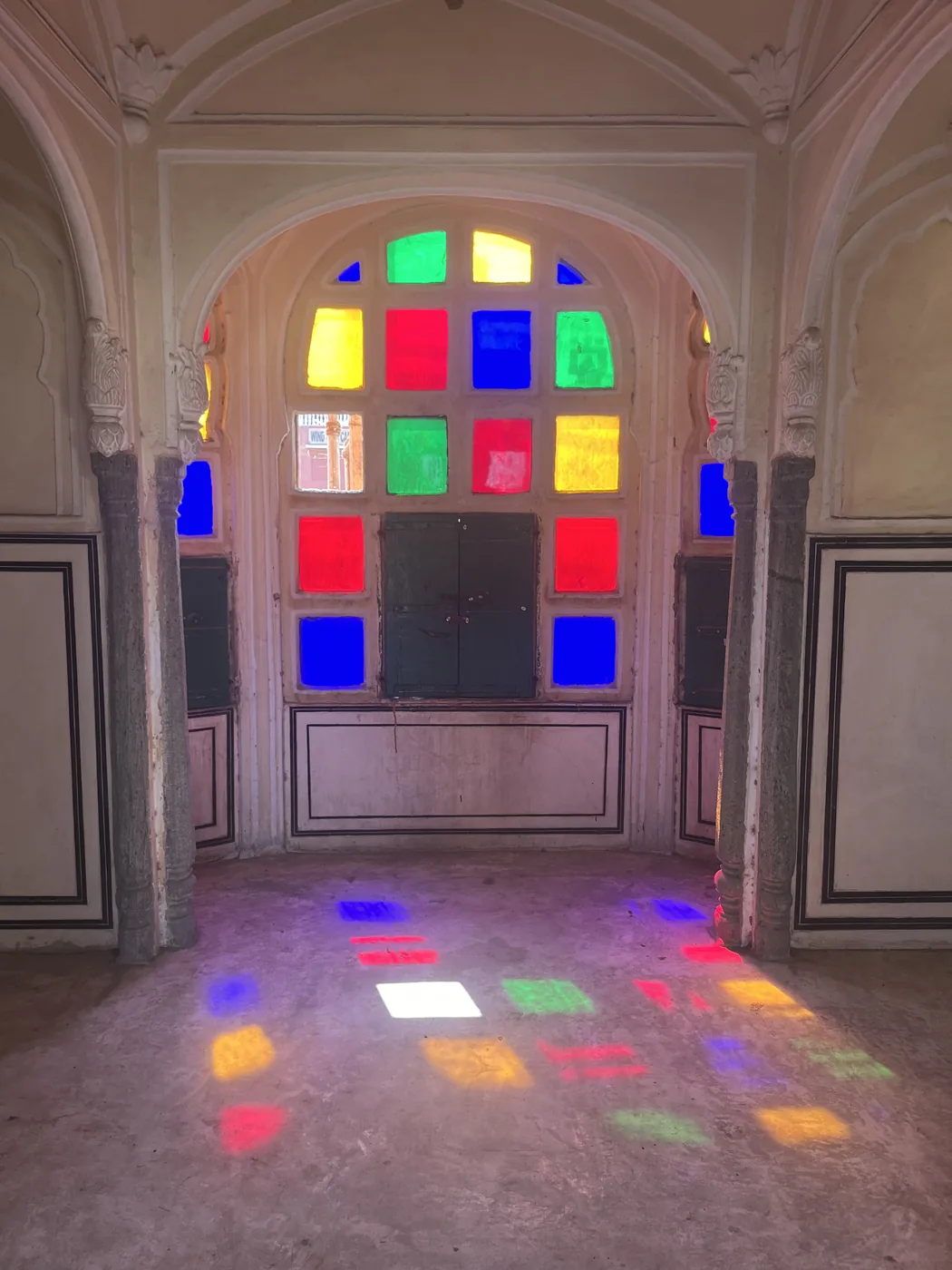 Coloured light from stained glass windows on the floor inside Hawa Mahal