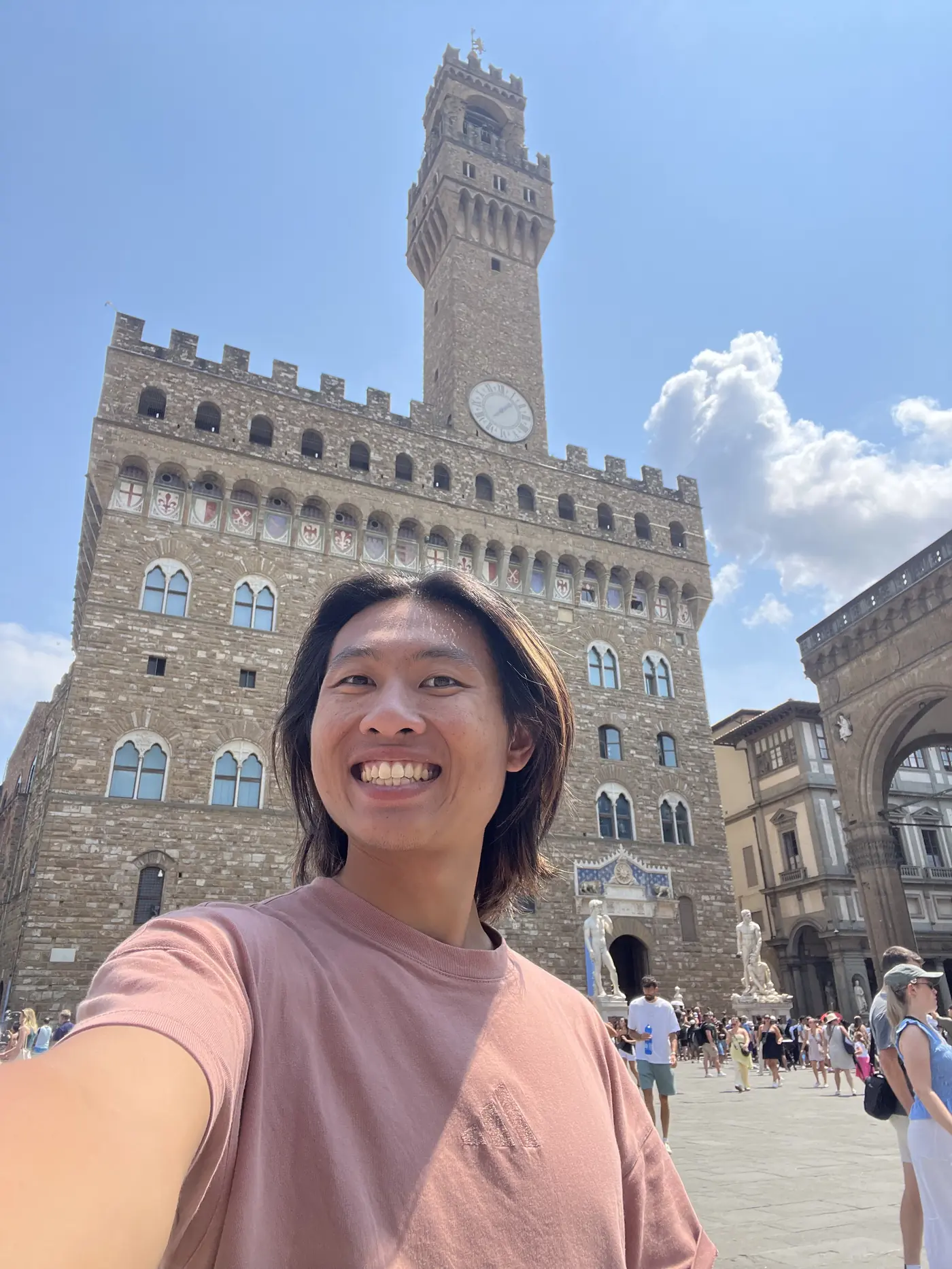 Shin selfie in front of the Palazzo Vecchio's fortress-like facade and clock tower in Piazza della Signoria, Florence