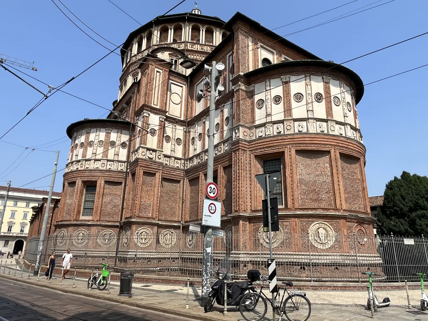 The red-brick Renaissance exterior of Santa Maria delle Grazie in Milan, home to Leonardo's Last Supper, with a domed apse and tiled roofs