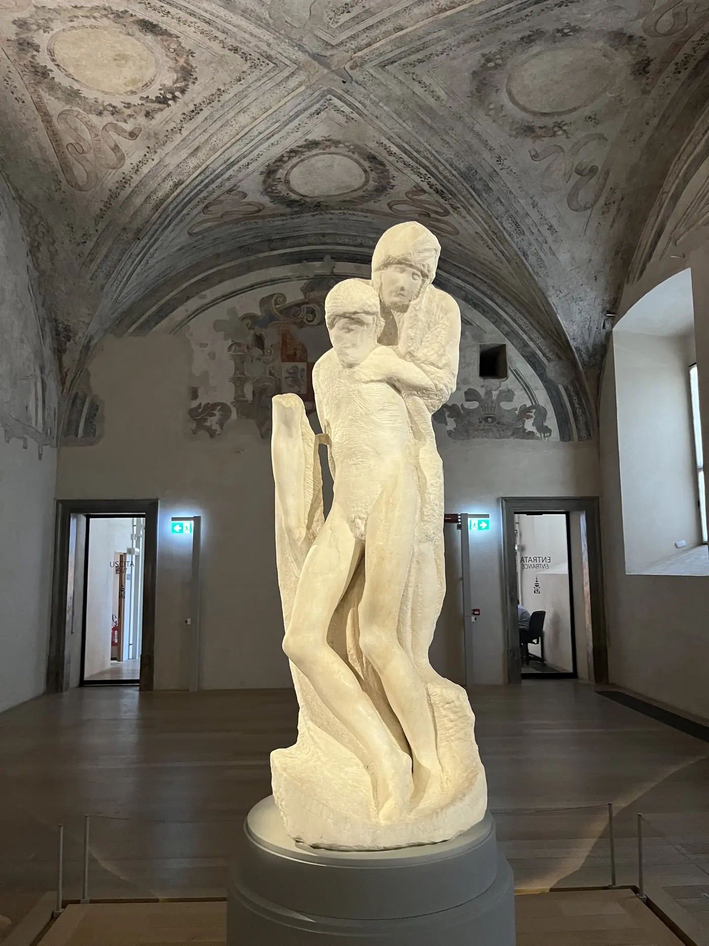Michelangelo's unfinished Rondanini Pietà marble sculpture displayed in a vaulted gallery room at Sforza Castle, Milan