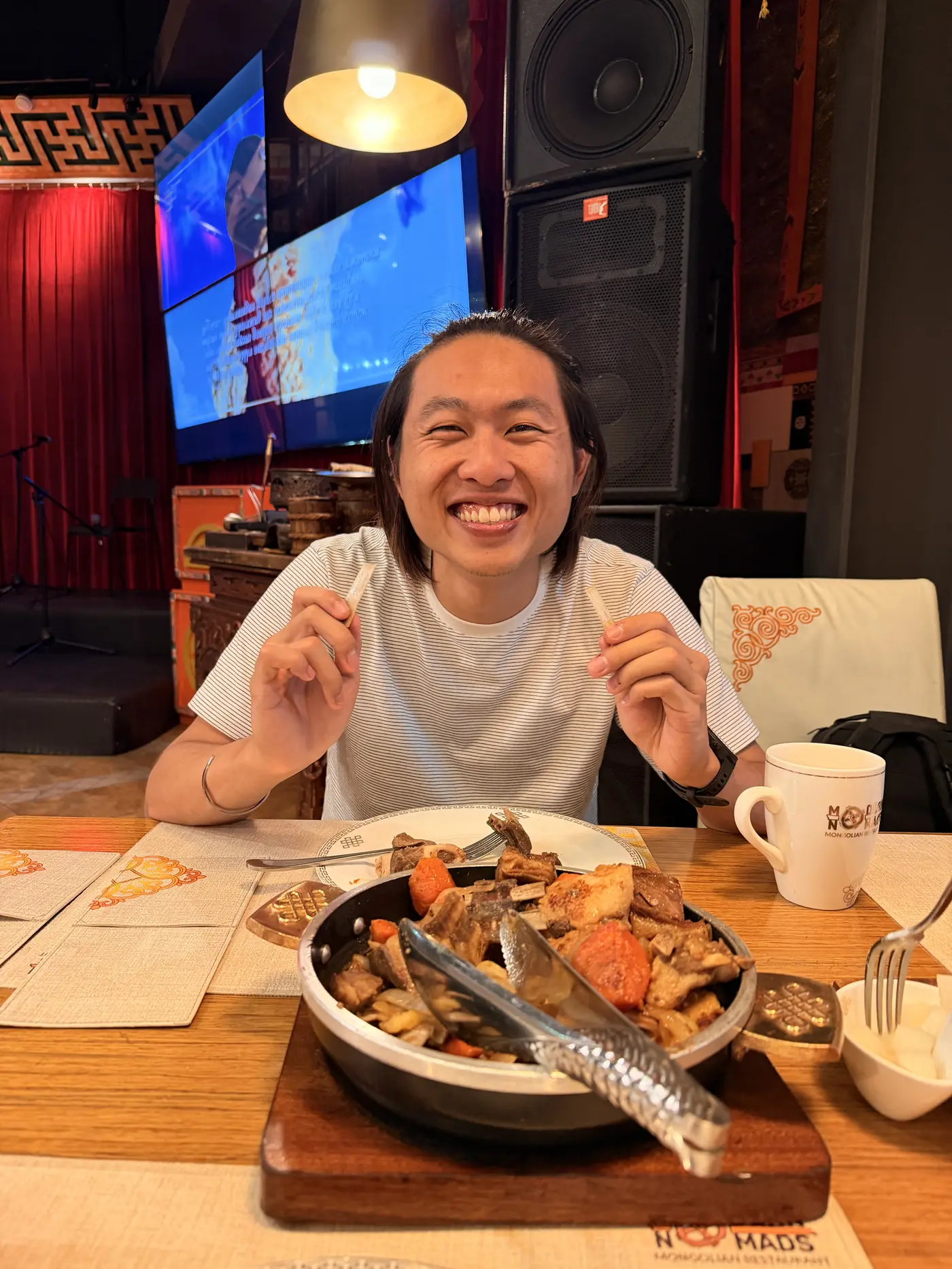 Shin grinning over a sizzling hot plate of grilled meat and vegetables at Nomads restaurant, Ulaanbaatar, Mongolia