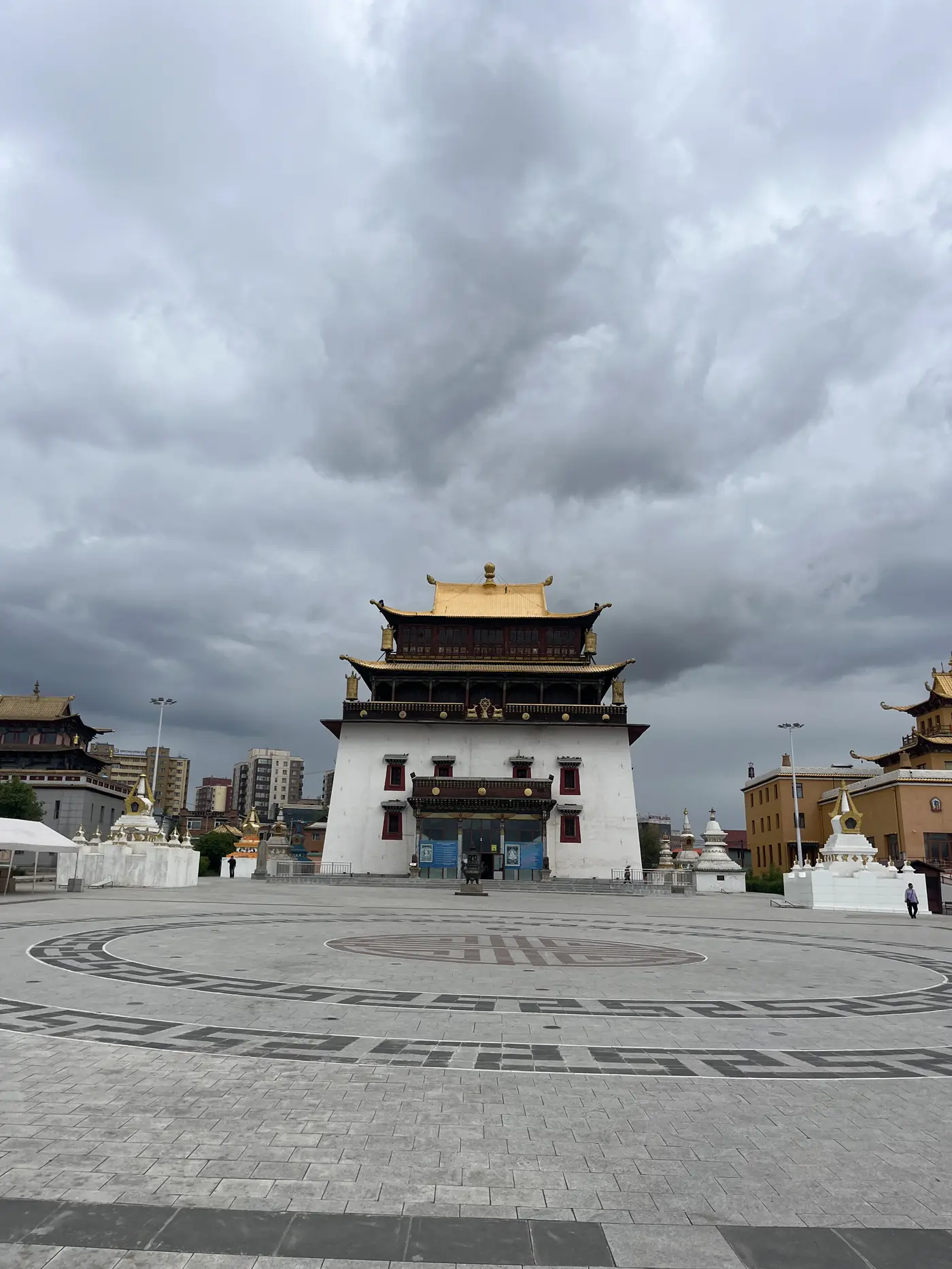 Gandan Monastery (Gandantegchinlen Khiid) in Ulaanbaatar, Mongolia under dramatic stormy sky with golden roof and white stupas