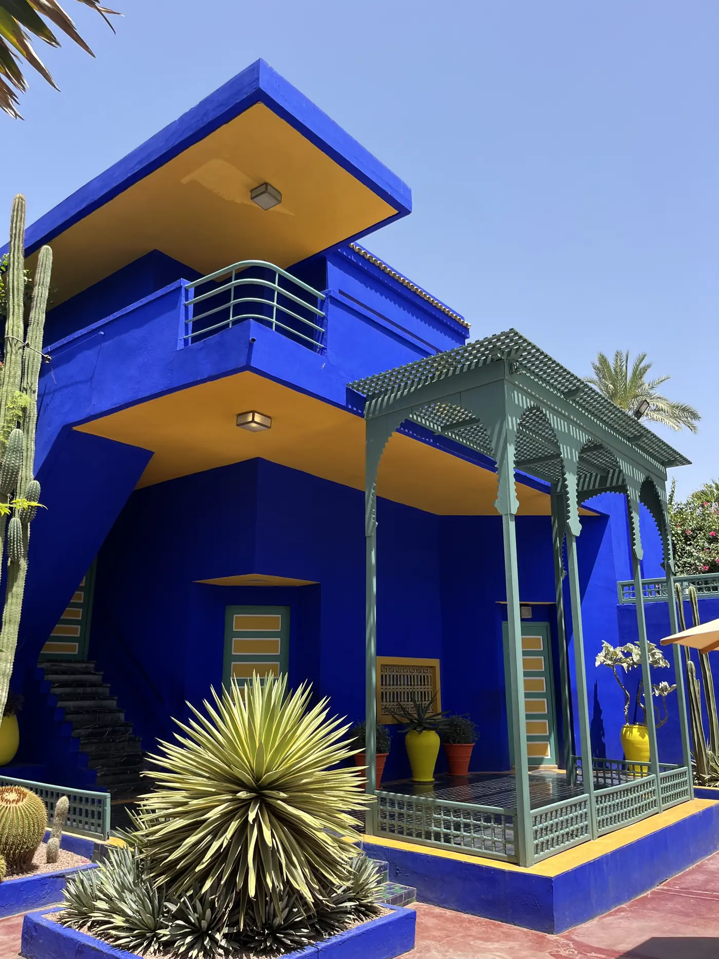 The cobalt blue and mustard yellow art deco villa and studio building at Jardin Majorelle, Marrakech, surrounded by cacti