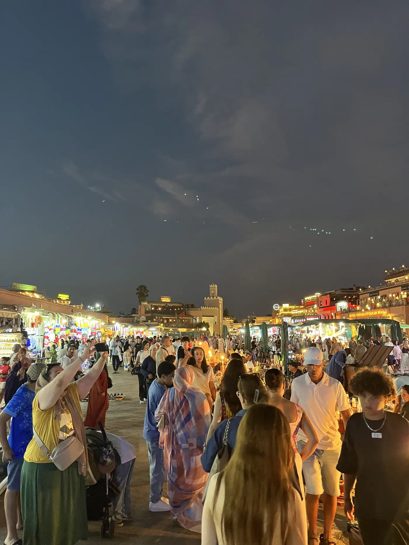 Jemaa el-Fnaa square in Marrakech at night, crowds moving between illuminated food stalls and market lights