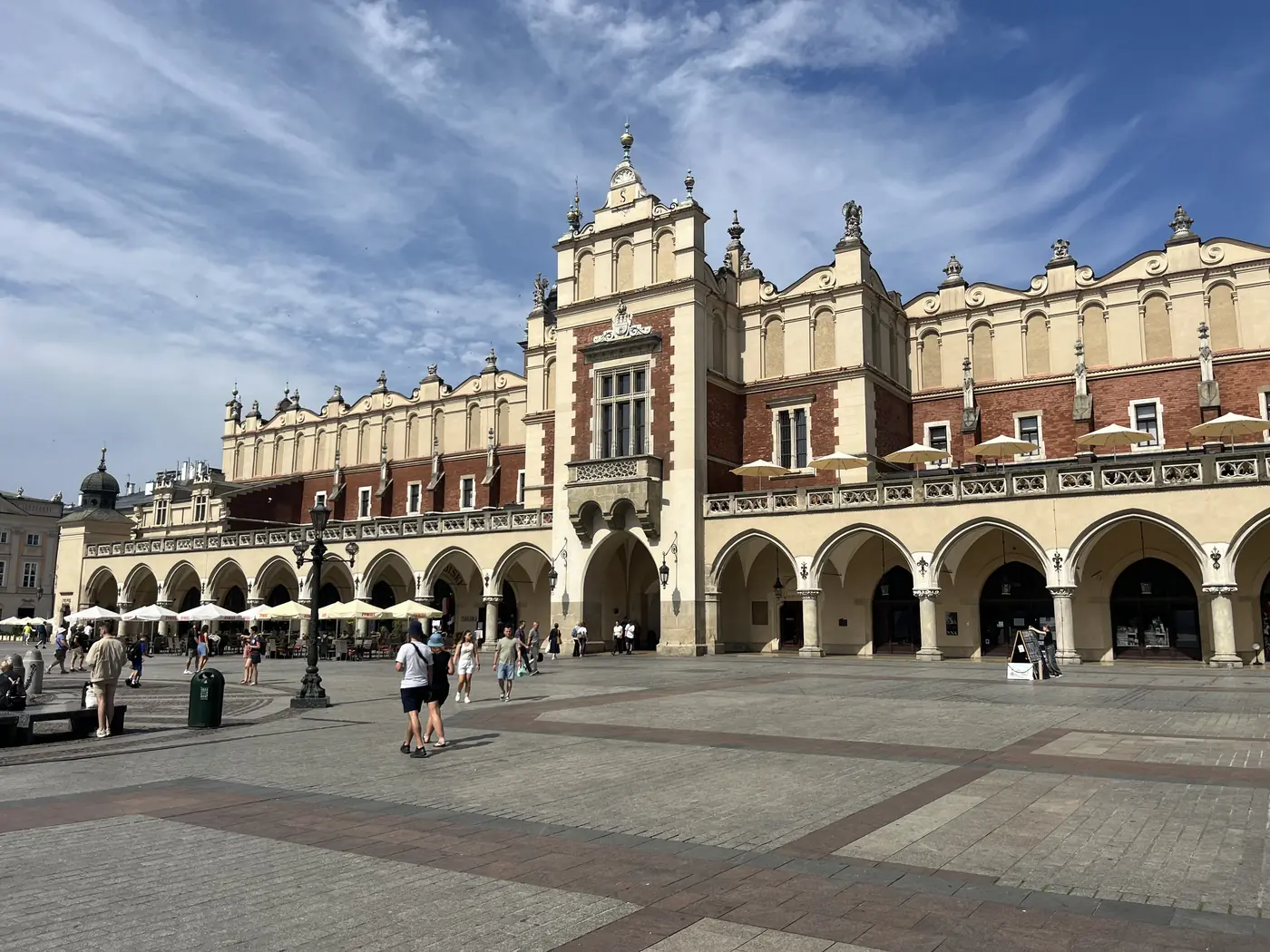 The Cloth Hall (Sukiennice) in Kraków's Main Market Square, Renaissance arcades and ochre facade under a wide blue sky