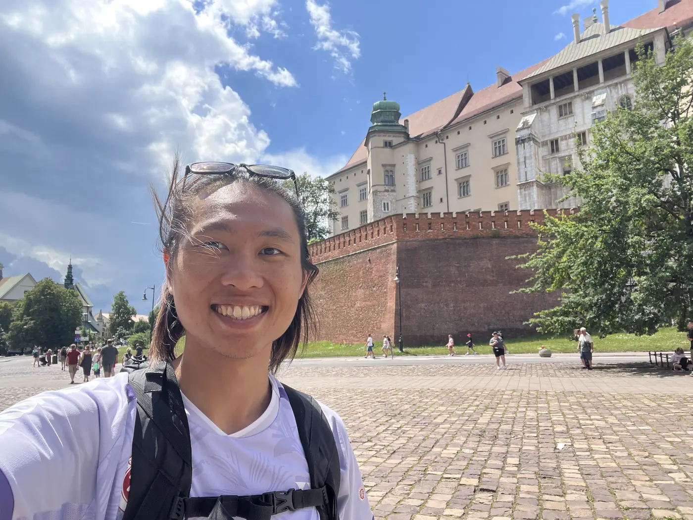 Shin selfie in front of Wawel Castle's red-roofed royal buildings and fortified brick wall on Wawel Hill, Kraków