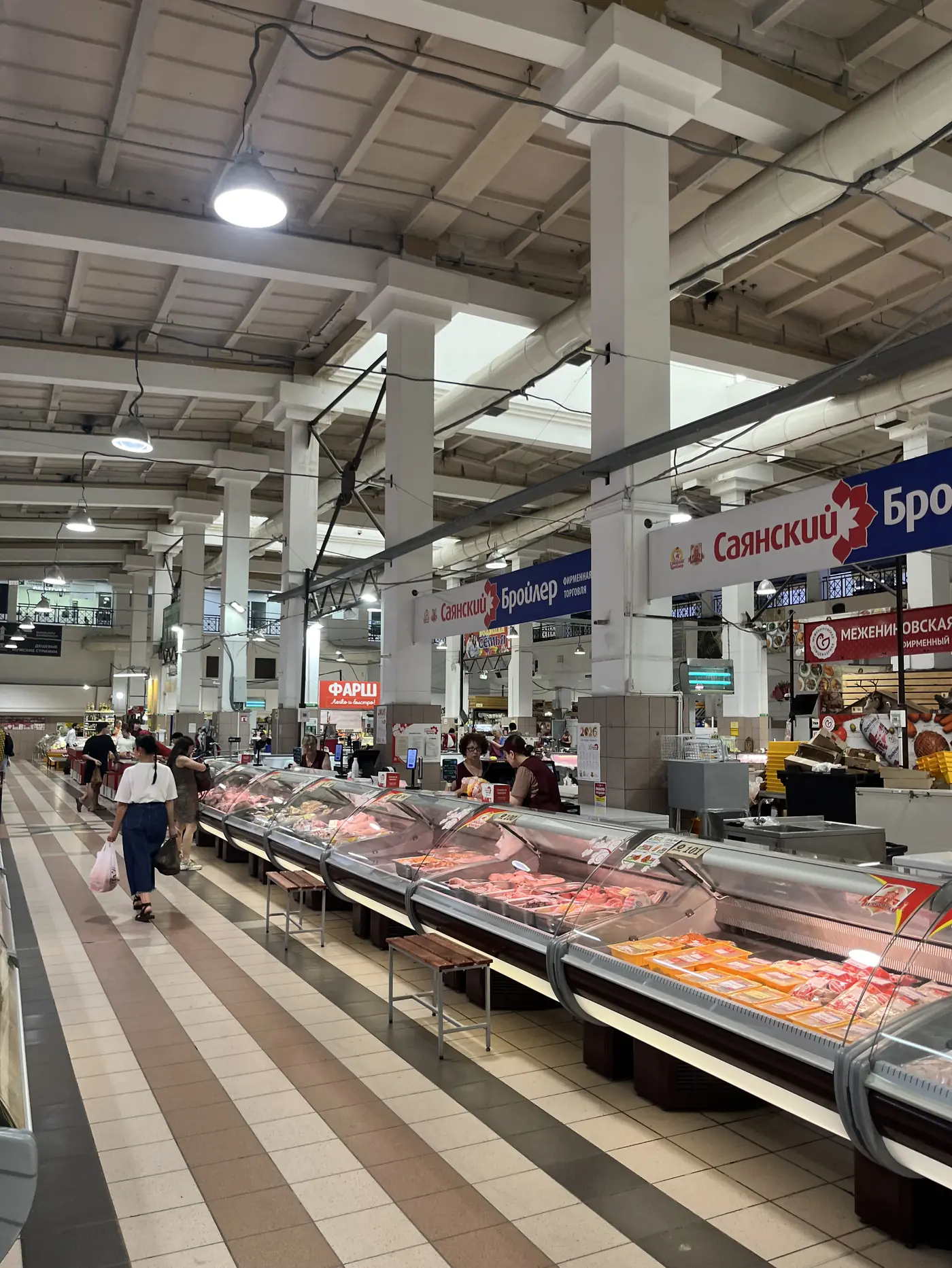 Indoor central market in Irkutsk with rows of meat counters and Russian Cyrillic signage, local food market in Siberia