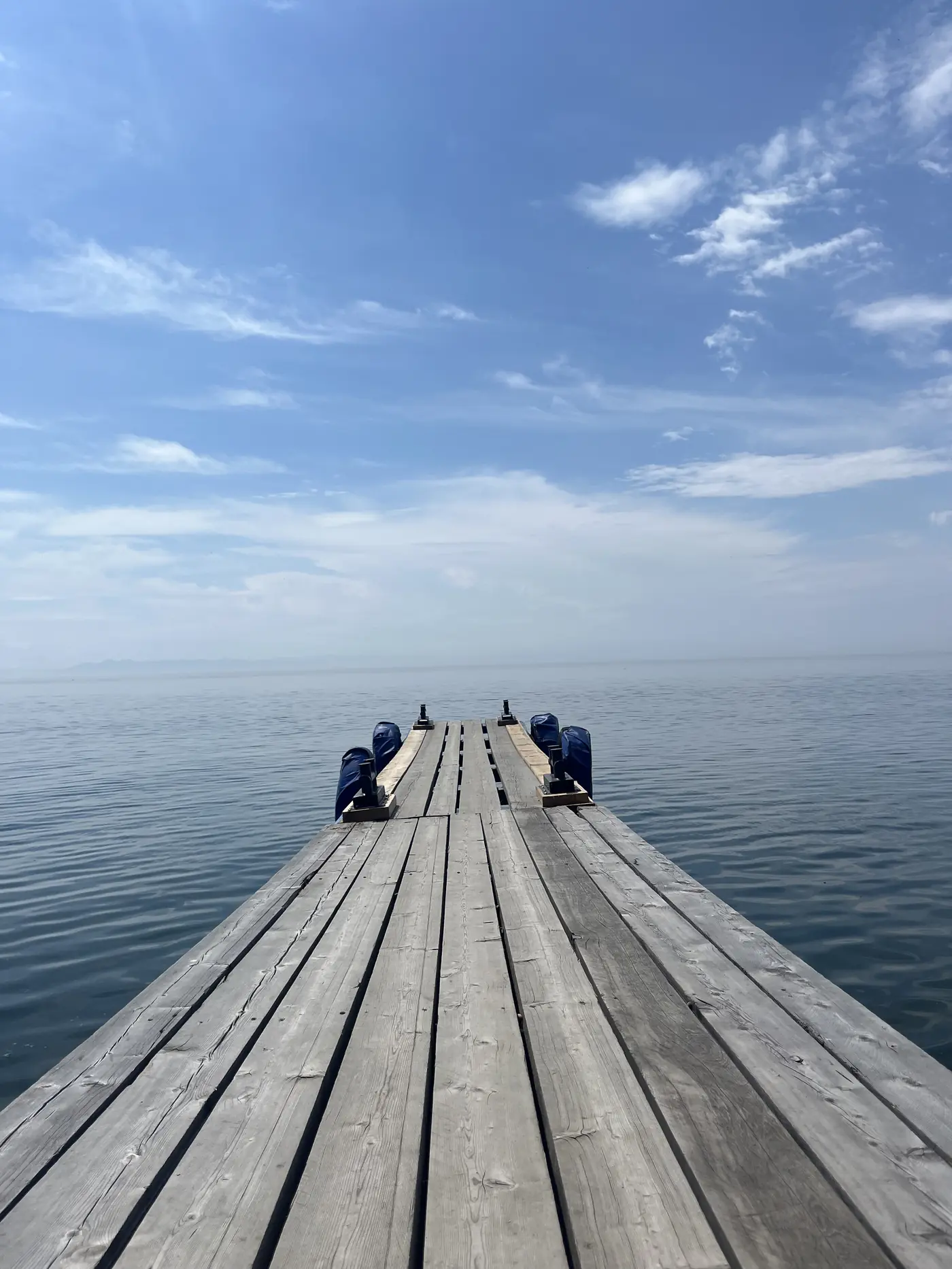 Wooden jetty pier extending into the glassy waters of Lake Baikal at Listvyanka, Siberia Russia, leading-line perspective into the horizon