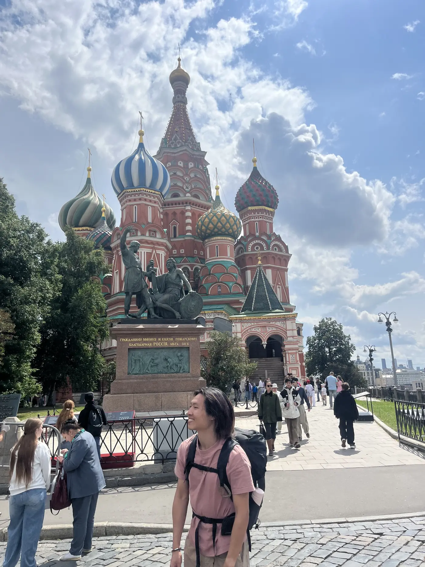 Shin standing in front of St. Basil's Cathedral on Red Square, Moscow, pink t-shirt, backpack, summer day