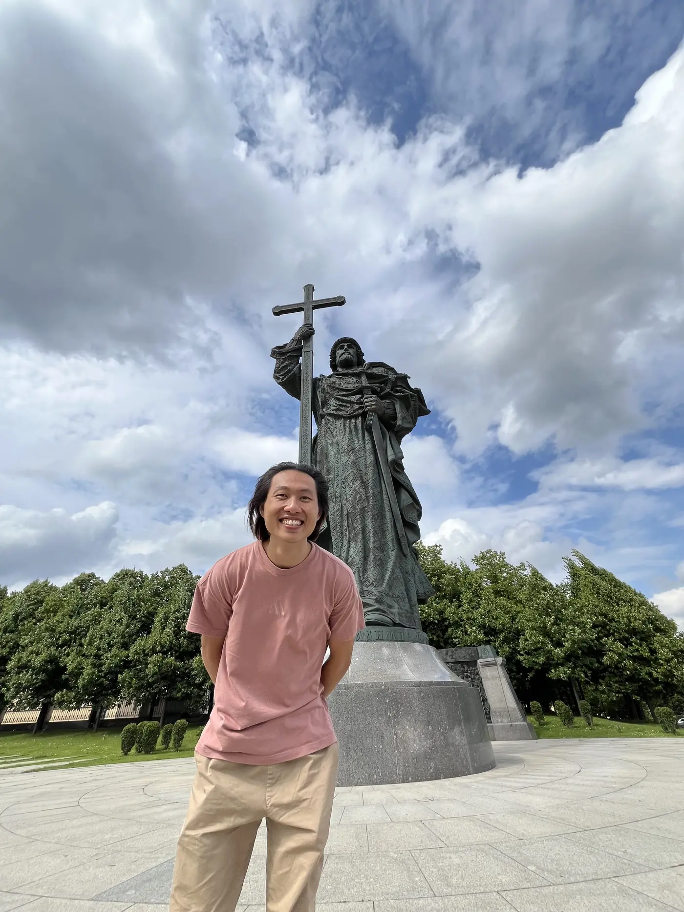 Shin in front of the bronze statue of Vladimir the Great holding a cross, near the Kremlin, Moscow, under dramatic clouds