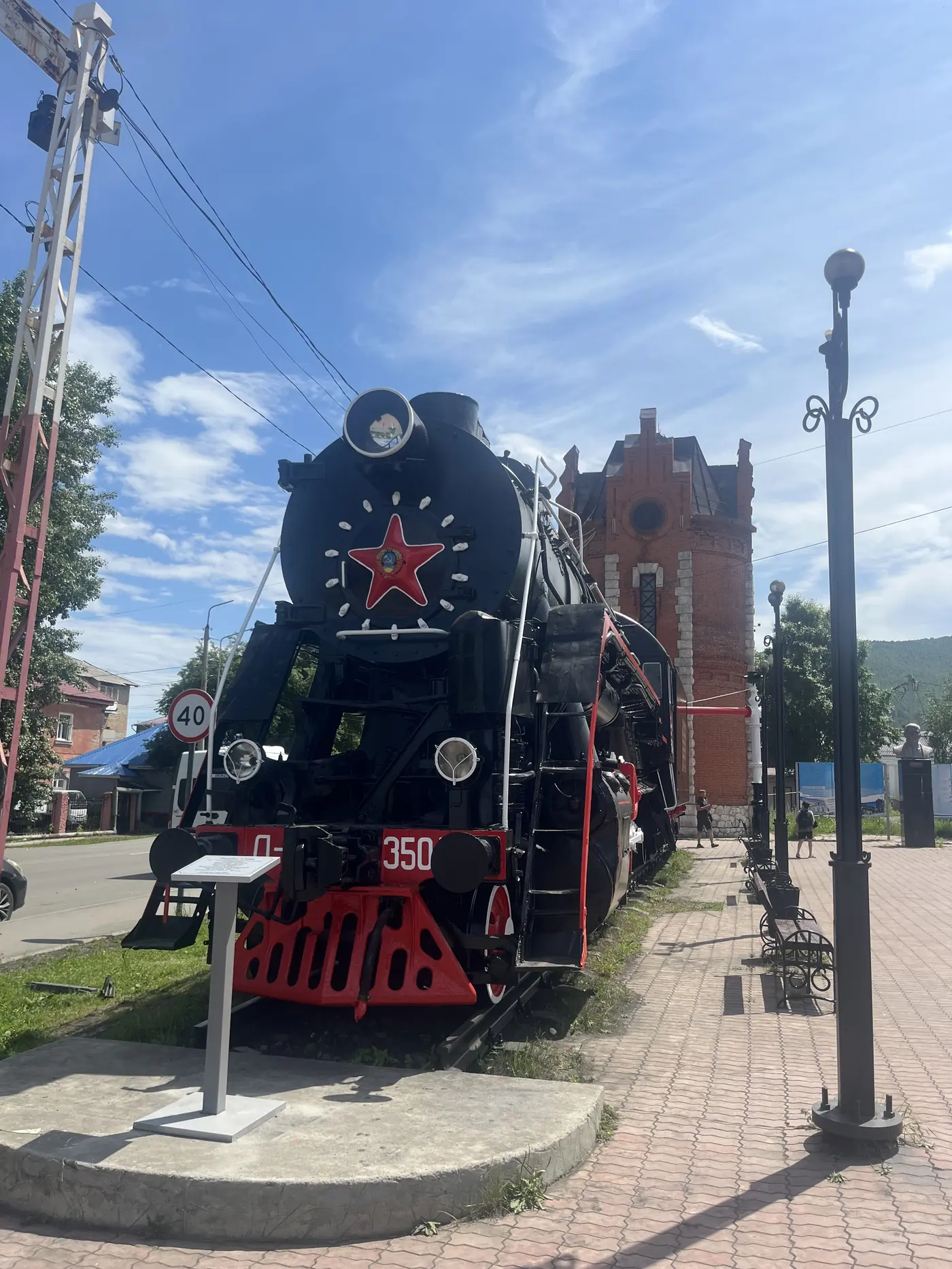 Black Soviet-era steam locomotive with a red star on the boiler, on display outside Slyudyanka's marble railway station, Siberia Russia