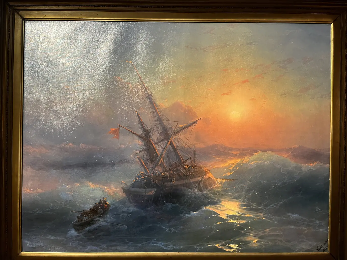 Aivazovsky oil painting of a tall sailing ship battling a stormy sea at fiery sunset, displayed in a St. Petersburg museum