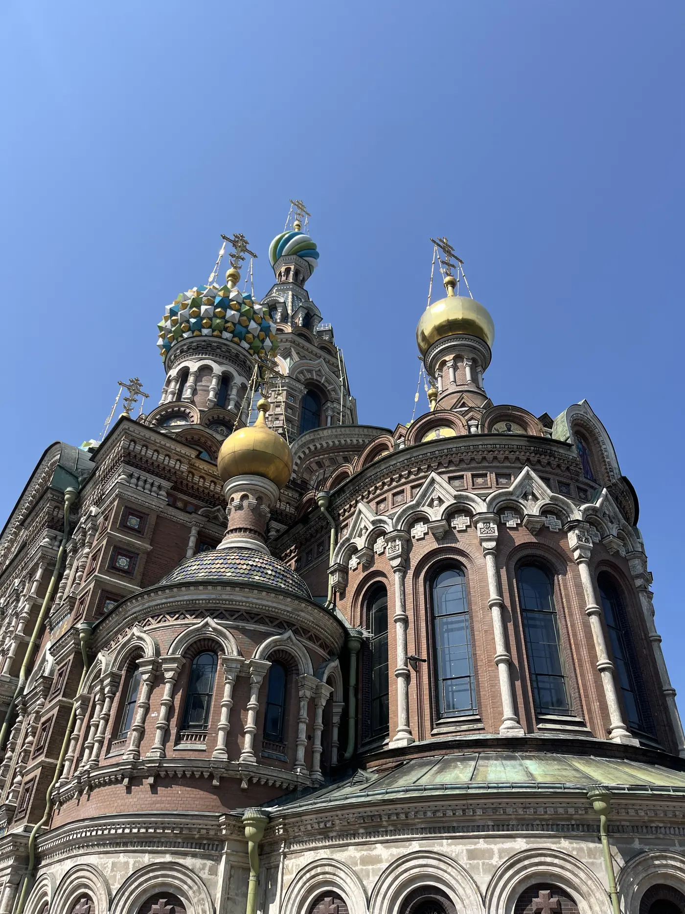 Close-up of the colourful onion domes and patterned brickwork of the Church of the Saviour on Spilled Blood, St. Petersburg, under a clear sky