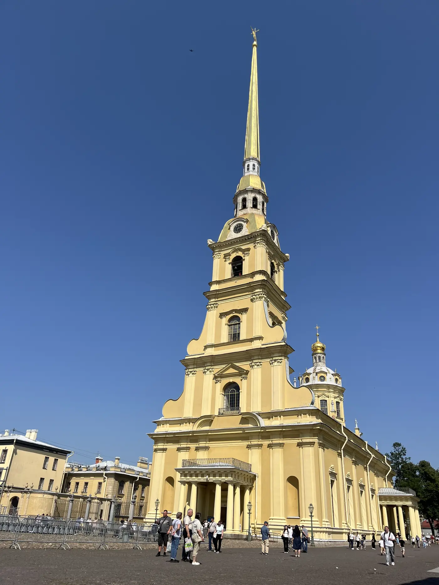 Peter and Paul Cathedral inside the Peter and Paul Fortress, yellow baroque facade with an impossibly tall golden spire piercing a deep blue sky