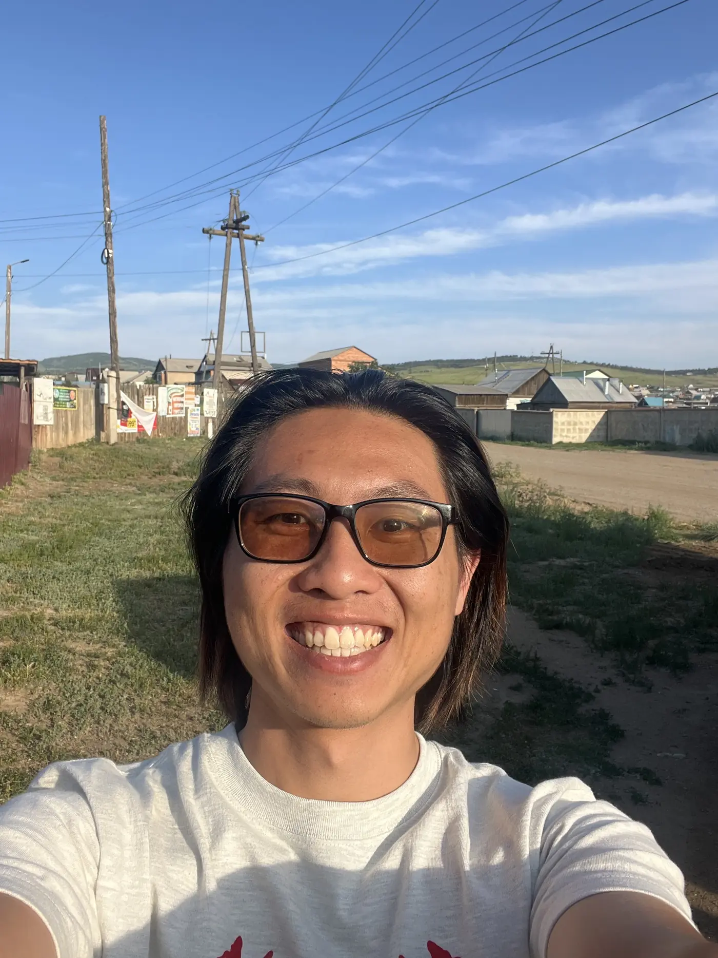 Shin selfie in a residential street in Ulan-Ude, Buryatia, Russia, wooden houses and power lines, warm evening golden light