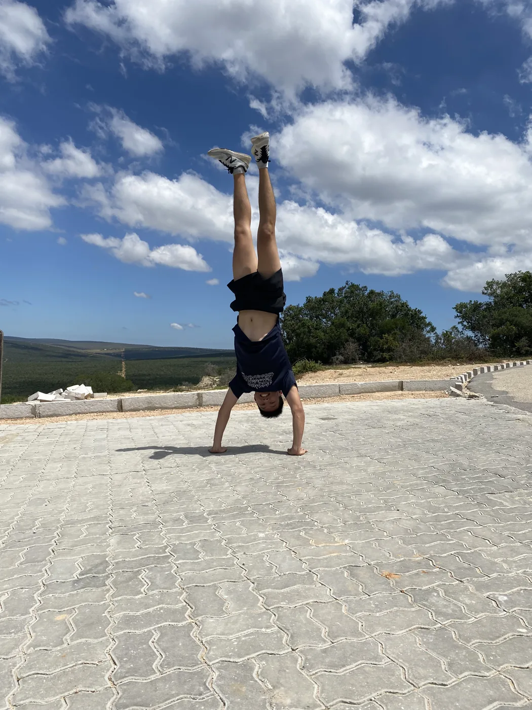 Person doing a handstand on a paved viewpoint with open South African landscape behind