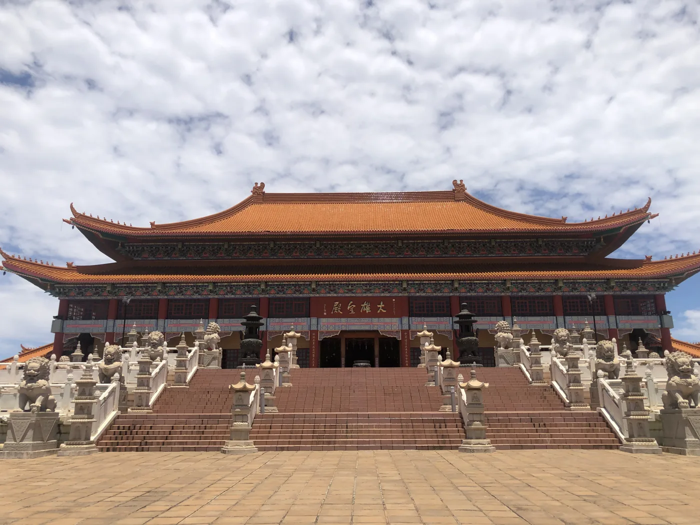 Grand Chinese-style Buddhist temple with sweeping roof tiers under a blue sky