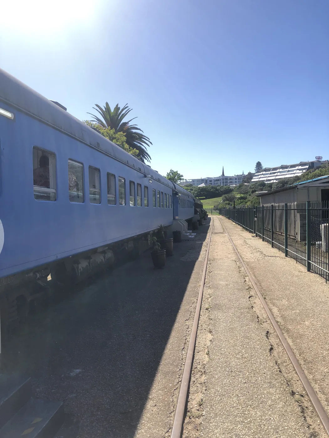 Vintage blue train carriage on tracks under a clear blue sky