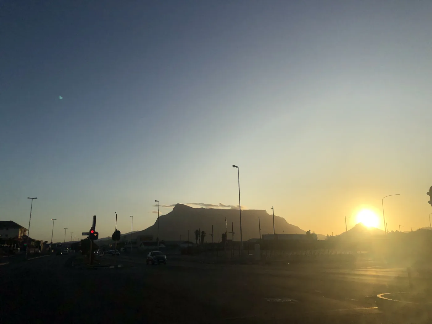 Table Mountain silhouette against a golden sunset sky from a Cape Town street