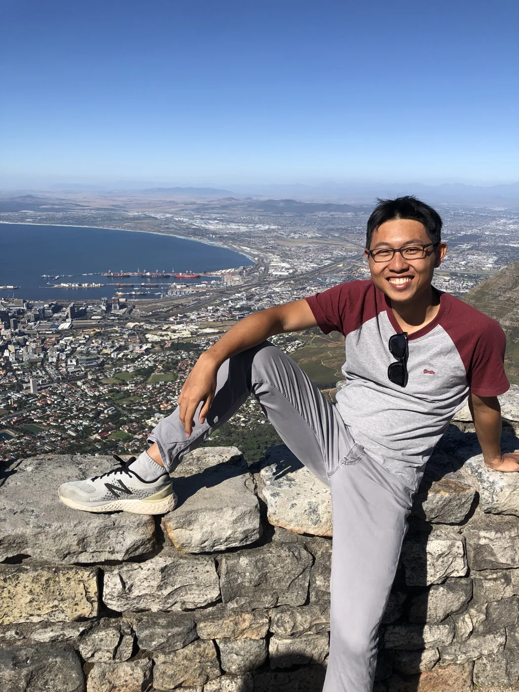Sitting on Table Mountain's summit wall with Cape Town and harbour panorama behind