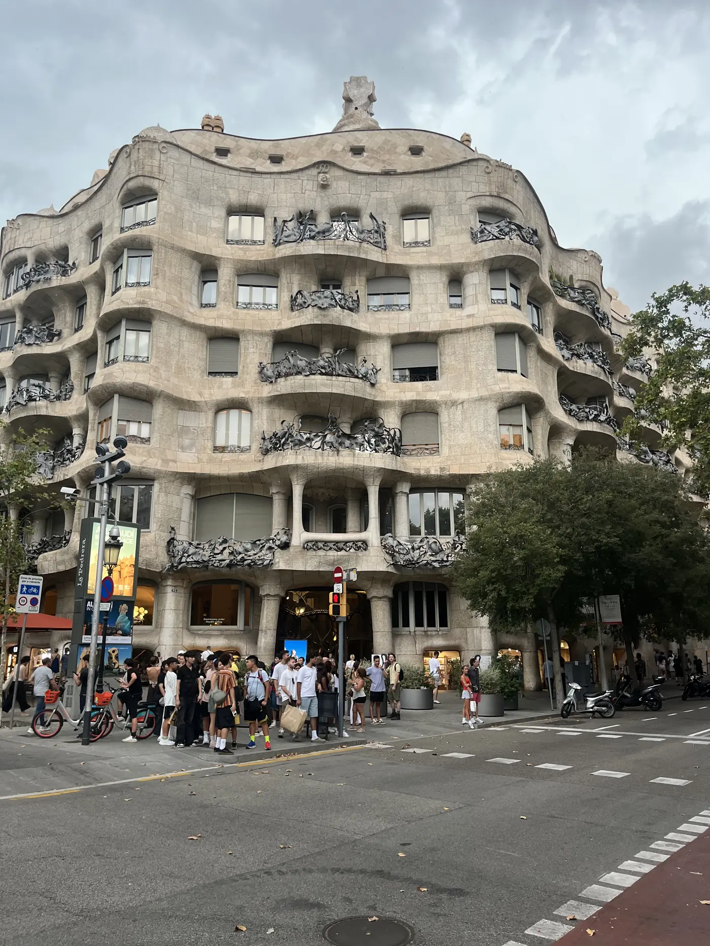 Casa Milà (La Pedrera), Gaudí's wave-like stone facade with wrought-iron balconies, crowds gathered outside on Passeig de Gràcia