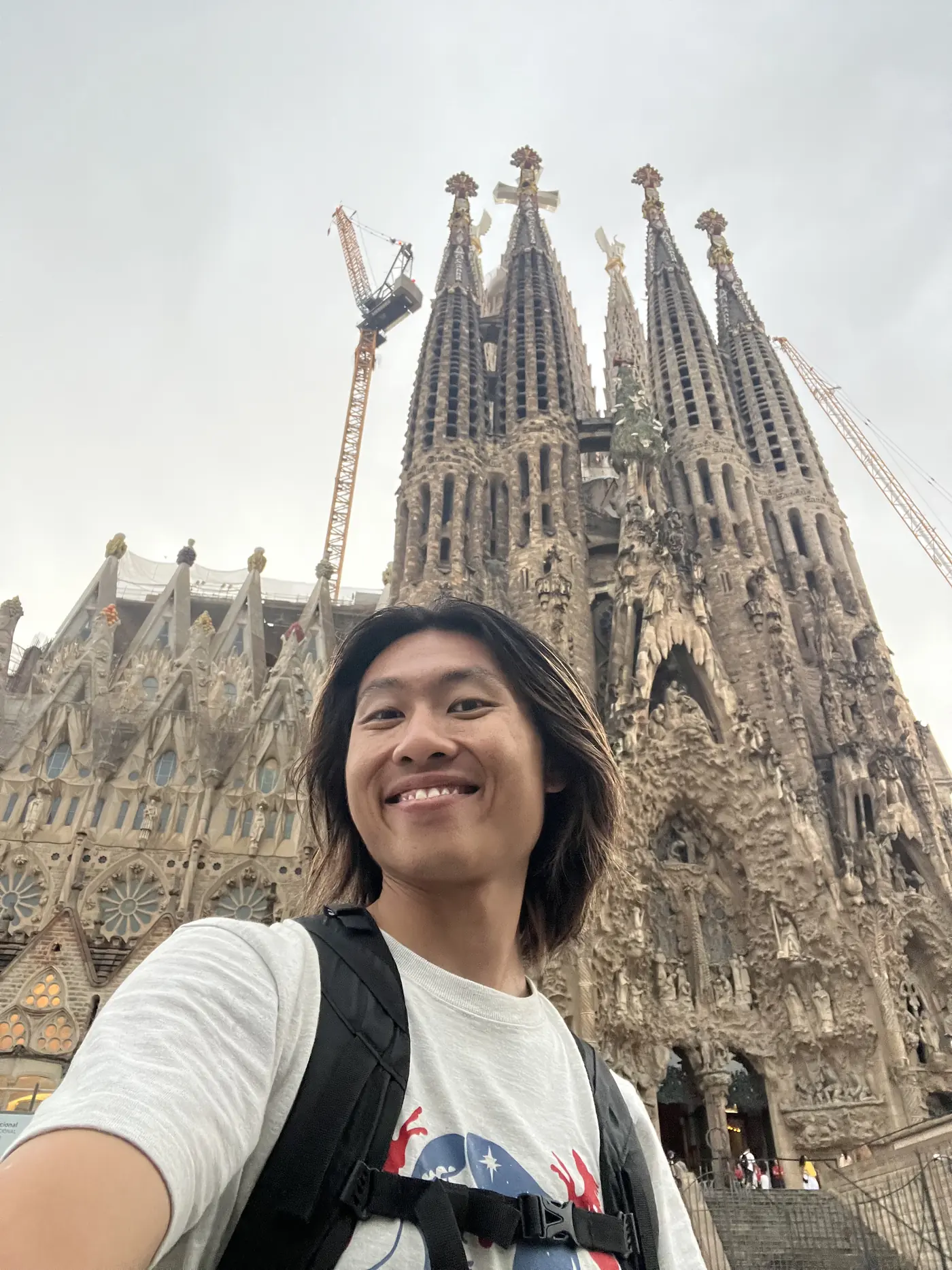 Shin selfie in front of the Sagrada Família's Gothic spires, cranes still working above the unfinished towers