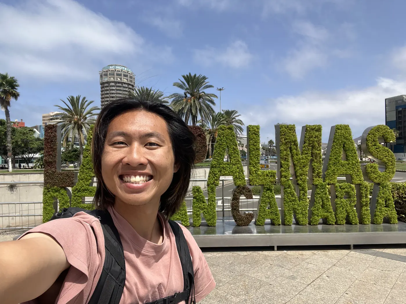 Shin selfie in front of the giant Las Palmas de Gran Canaria living-letters sign, palm trees and city skyline behind