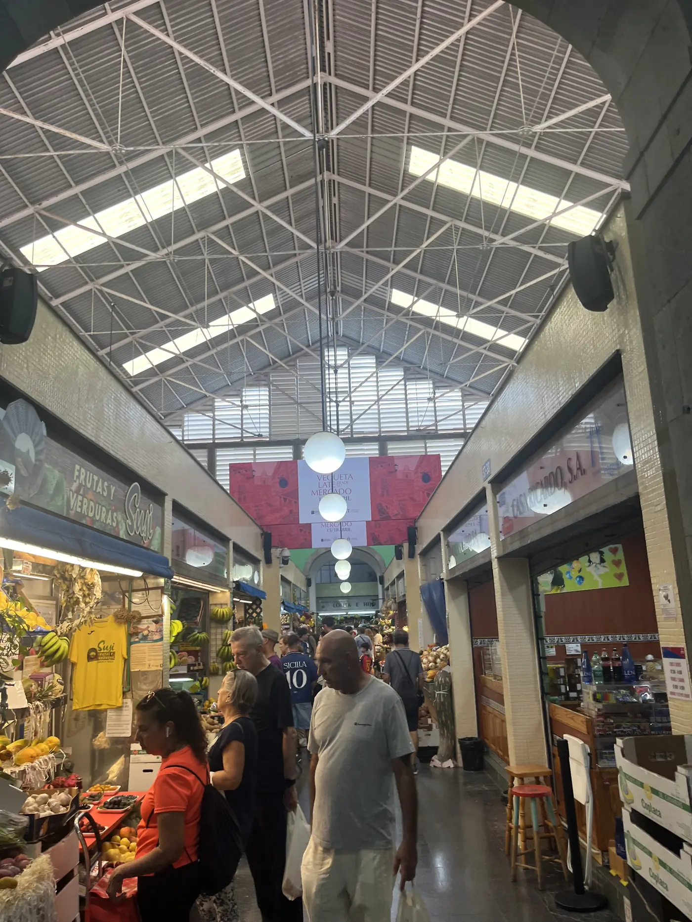 Interior of the Mercado de Vegueta in Las Palmas, a covered market hall with arched steel roof, fruit stalls, and shoppers
