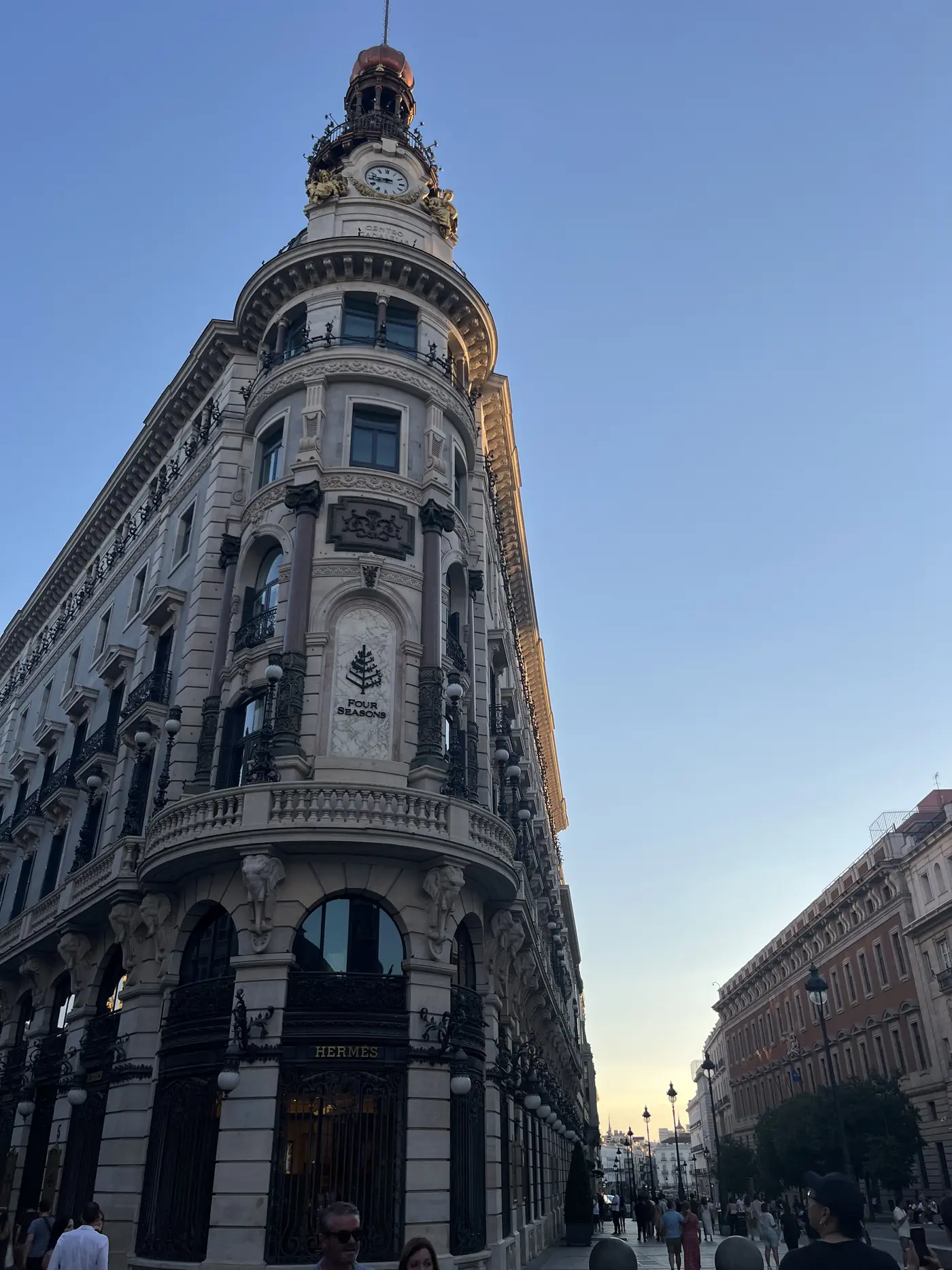 The ornate turreted Canalejas building near Puerta del Sol, Madrid, housing the Four Seasons hotel and a Hermès storefront, evening light