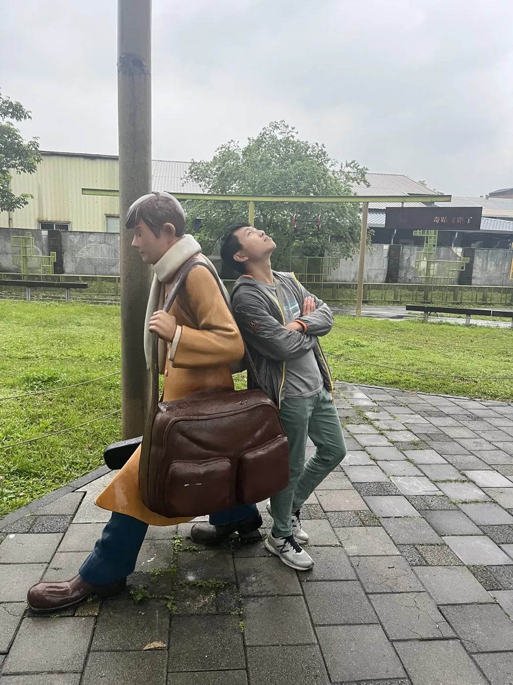 Posing with a monk statue in a rainy park, Taiwan