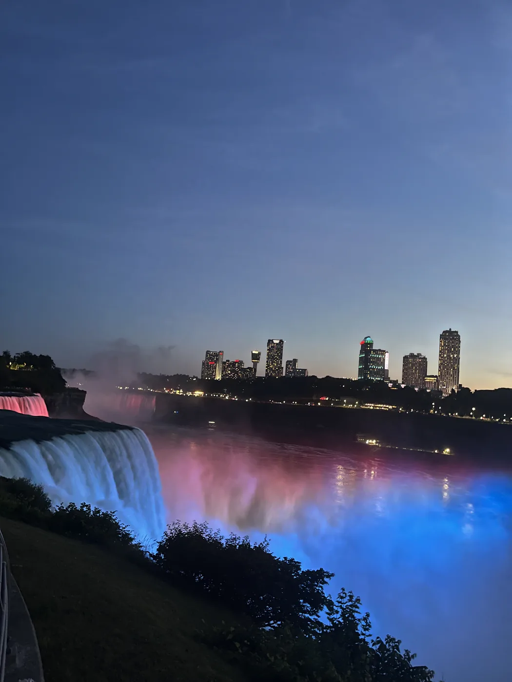 Niagara Falls illuminated in red and blue at dusk