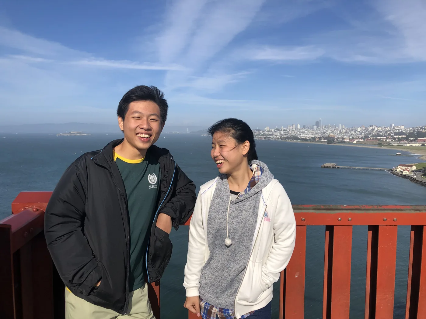 Two friends laughing on the Golden Gate Bridge with San Francisco skyline behind