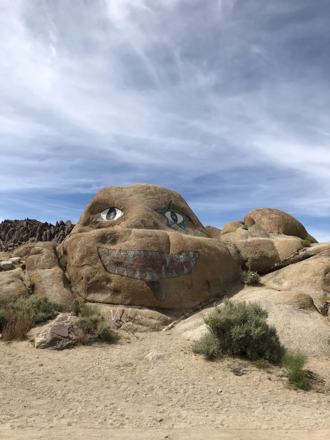 A giant boulder painted with a grinning face in Alabama Hills desert landscape