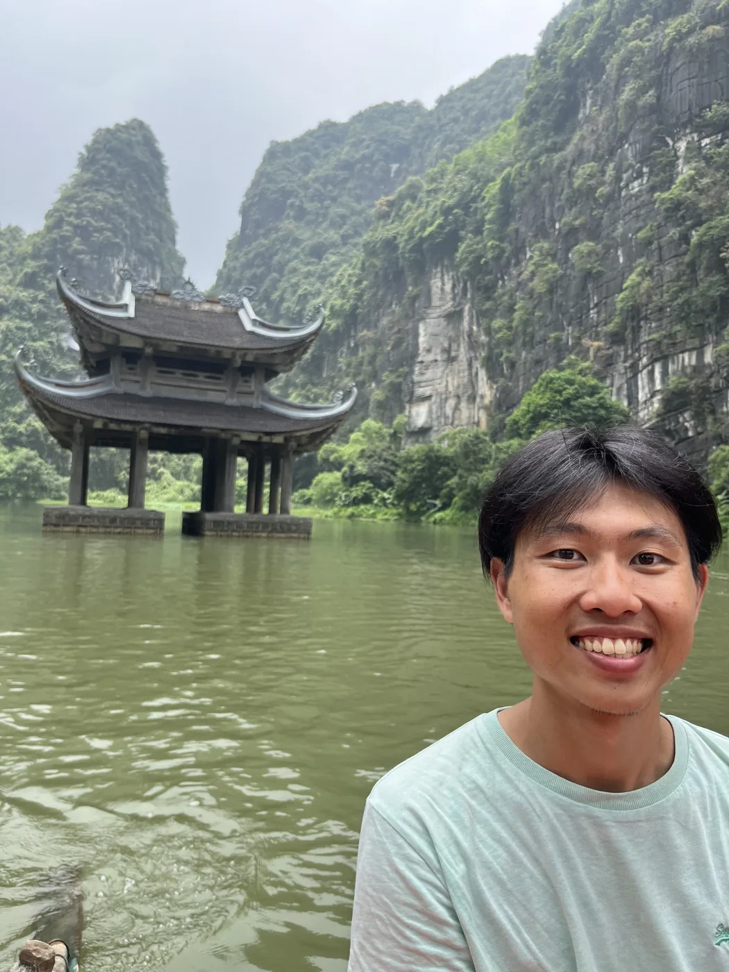 Selfie with flooded pavilion and karst cliffs at Trang An, Ninh Binh