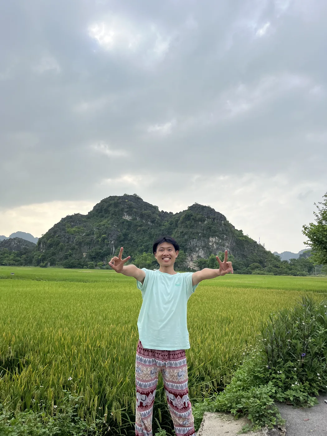 Arms wide open in front of rice fields and karst peaks, Ninh Binh