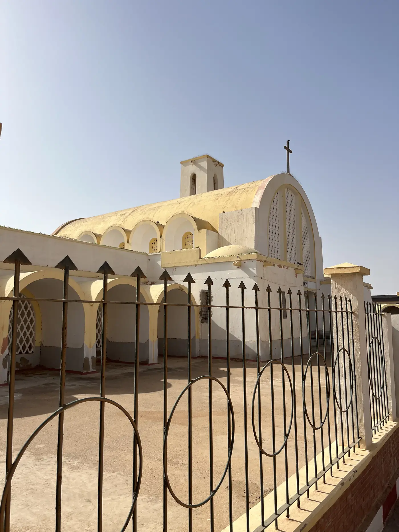 The white and yellow domed roof of the Spanish colonial-era Catholic church in Laayoune, seen from behind an iron fence