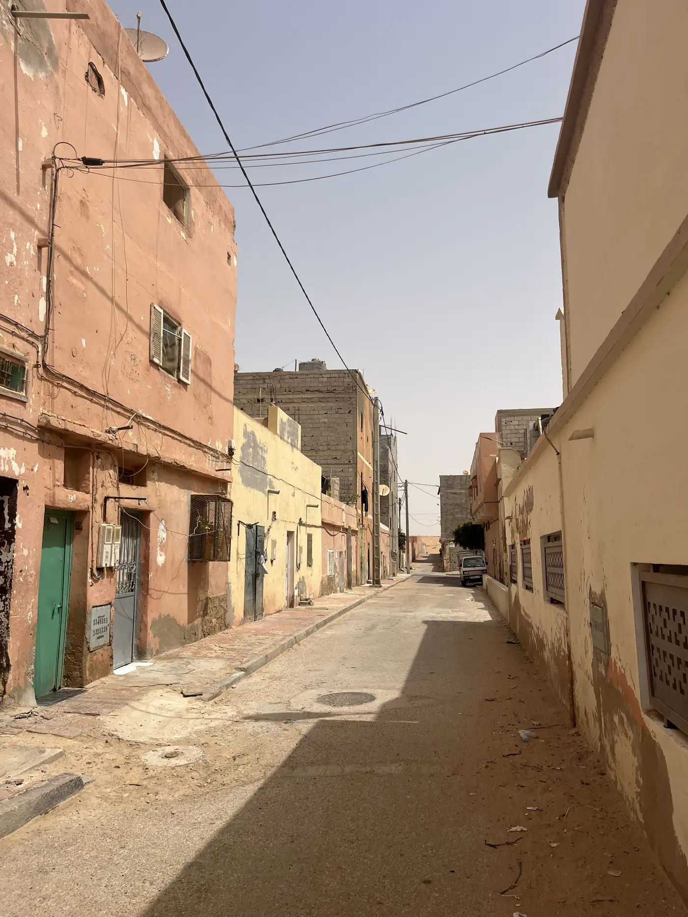 A narrow old-town alley in Laayoune lined with weathered salmon and cream-coloured buildings