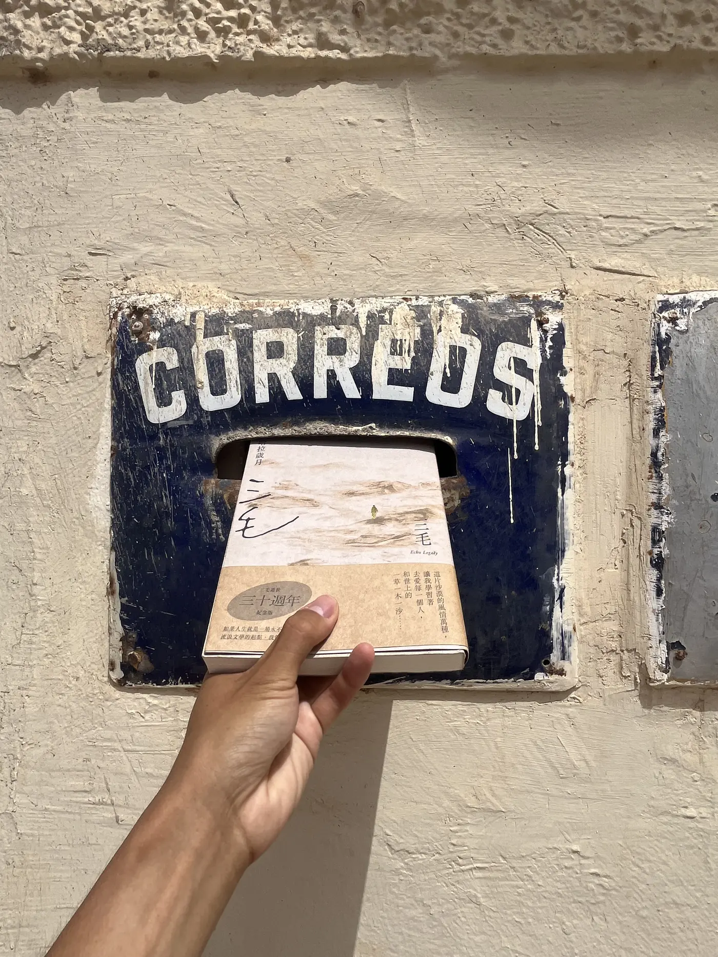 Close-up of Sanmao's book Stories of the Sahara tucked into the slot of an old Spanish 'Correos' postbox in Laayoune